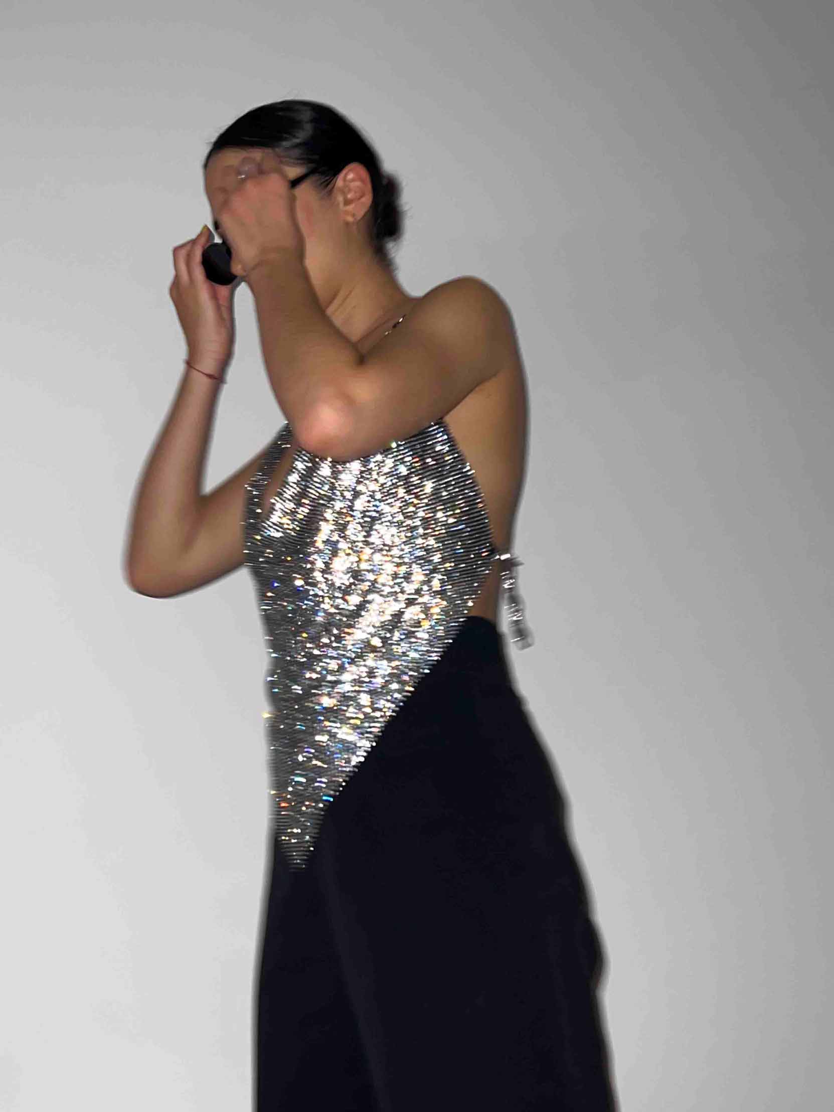 Model wears a chainmail crystal crop top in black and silver. Embellished cowl neckline top for party clothing and rave festival outfits. Edgy look.