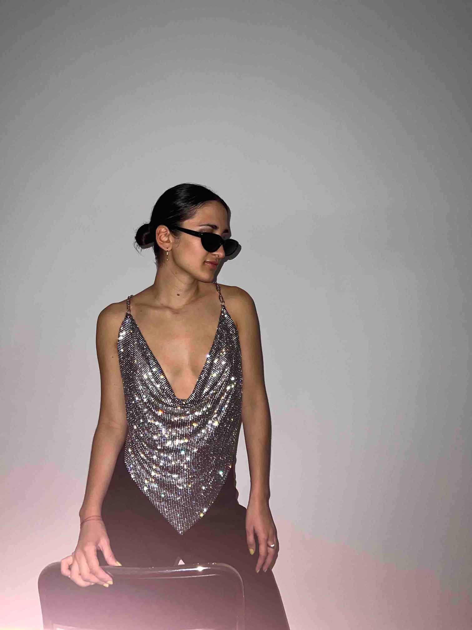 Model wears a chainmail crystal crop top in black and silver. Embellished cowl neckline top for party clothing and rave festival outfits.